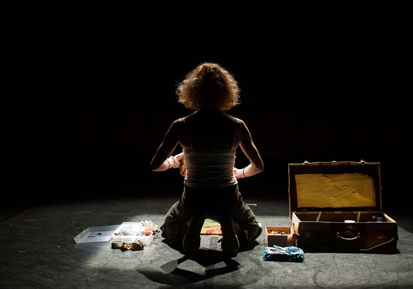 A woman kneeling packing her suitcase